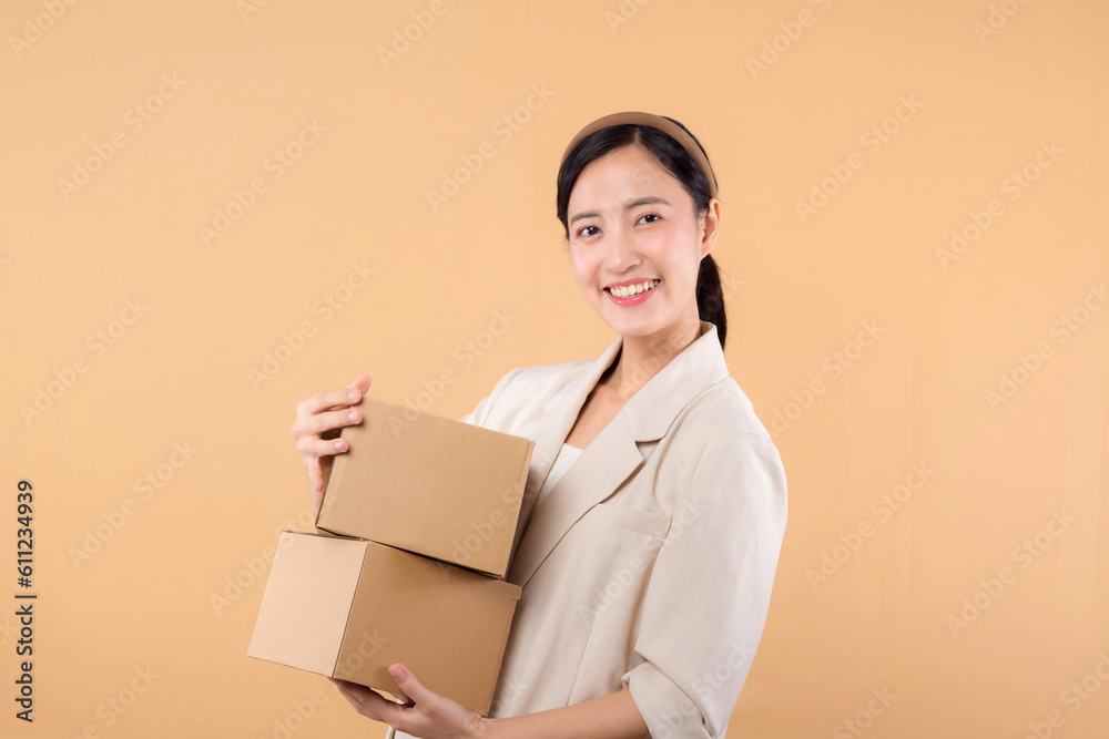 portrait of happy successful confident young asian business woman wearing white jacket holding parcel box isolated on beige studio background, Delivery courier and shipping service concept. portrait of happy successful confident young asian business woman wearing white jacket holding parcel box isolated on beige studio background, Delivery courier and shipping service concept.