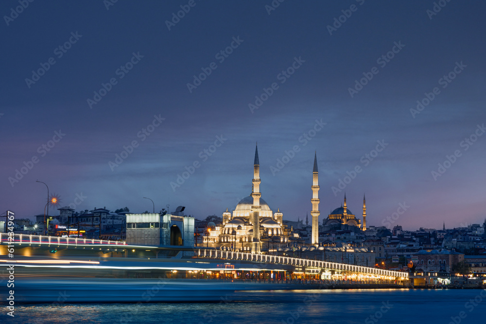 Long exposure of Istanbul at dusk with boats passing by Bosphorus canal and mosque. Scenic view of Istanbul in Turkey with Galata bridge at night.