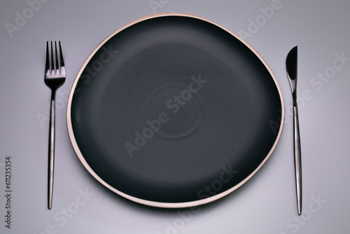 Black plate on the grey background. Copy space, top view.