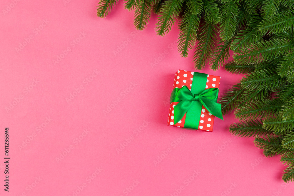 Top view of fir tree branches and gift box on colorful background. Christmas time concept with empty space for your design