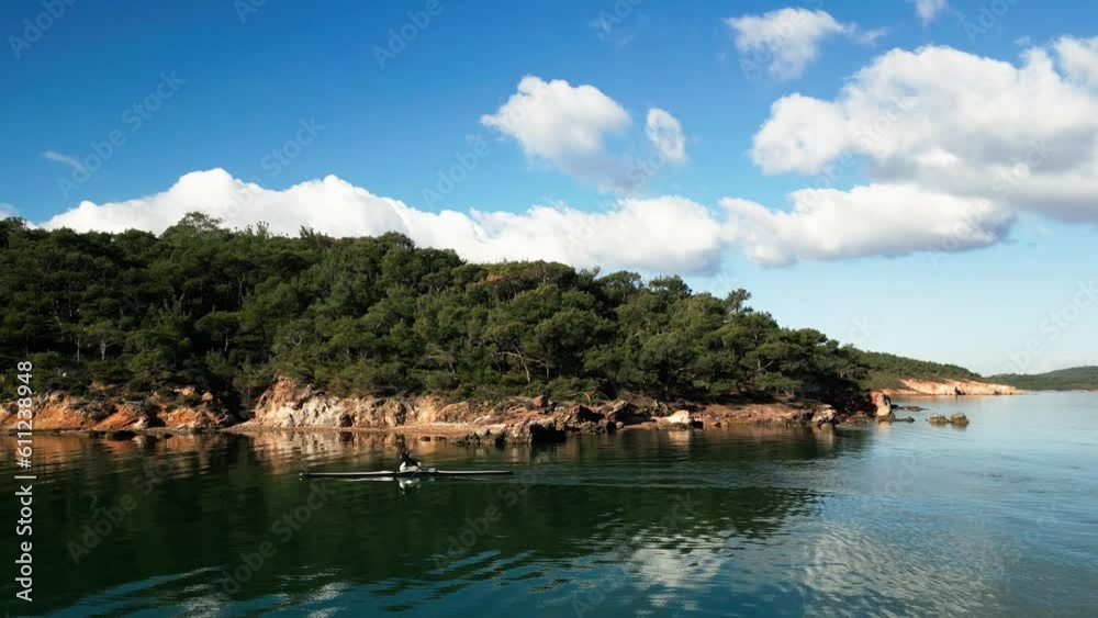 man rowing in the blue sea between mountains on a beautiful cloudy day. High quality 4k footage man rowing in the blue sea between mountains on a beautiful cloudy day. High quality 4k footage