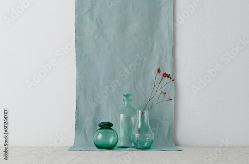 Horizontal shot of modern still life composition with glassware and dried flowers against white wall and blue linen fabric background, copy space