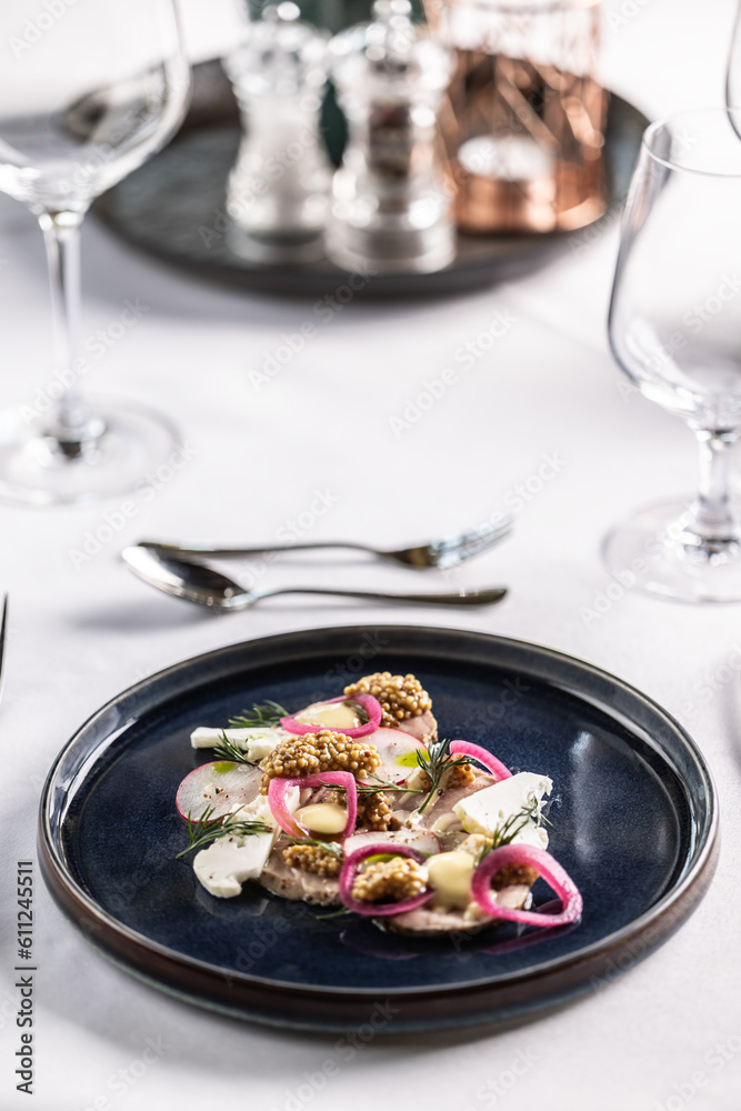 Restaurant appetizer with duck or goose liver pate with vegetable presented on a dark plate and white table Restaurant appetizer with duck or goose liver pate with vegetable presented on a dark plate and white table