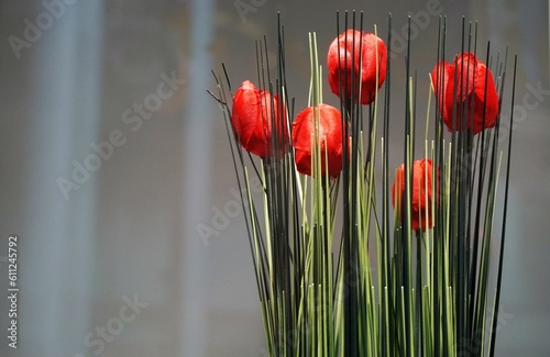 Roter Tulpenstrauß vor weiß-grauer durchsichtiger Gardine  photo