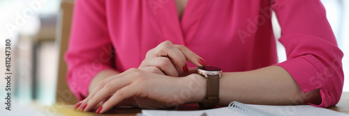 Business woman adjusting wrist watch at table in office closeup. Time management concept