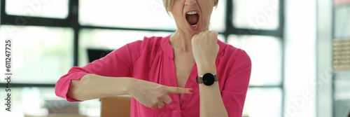 Woman manager screaming and pointing finger at wrist watch in office. Time management and being late at work concept
