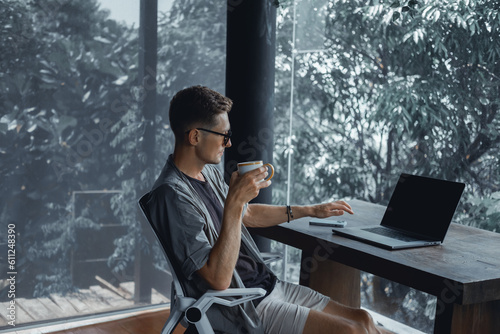Handsome man call in smartphone, happy face, outdoor hipster portrait on the cafe, smile happy face, listen music on headphones, text, messenger, hipster, player,photo concept, laptop, coffee cup