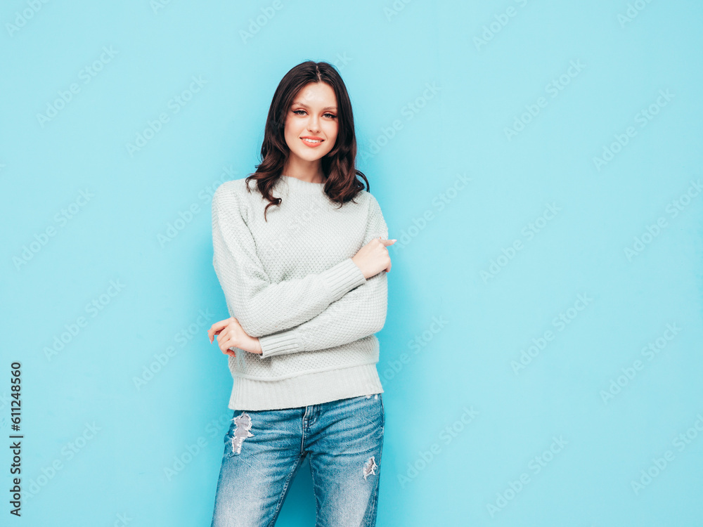 Young beautiful smiling female in trendy summer jeans and sweater clothes. Sexy carefree woman posing near blue wall in studio. Positive model isolated. Cheerful and happy Young beautiful smiling female in trendy summer jeans and sweater clothes. Sexy carefree woman posing near blue wall in studio. Positive model isolated. Cheerful and happy