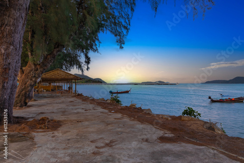 Sunset over Rawai Beach in Phuket island Thailand. Lovely turquoise blue waters, lush green mountains colourful skies and beautiful views the pier and long tail boats. Sky is taken seperate from Body  photo