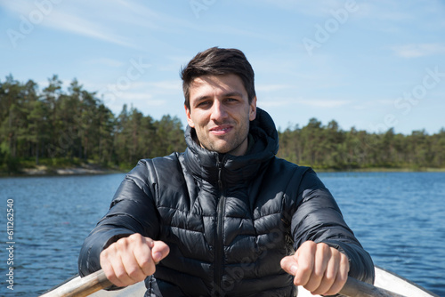 Portrait of a caucasian boy rowing on a bot in Sweden during a leisure holiday. Happiness and relax concepts