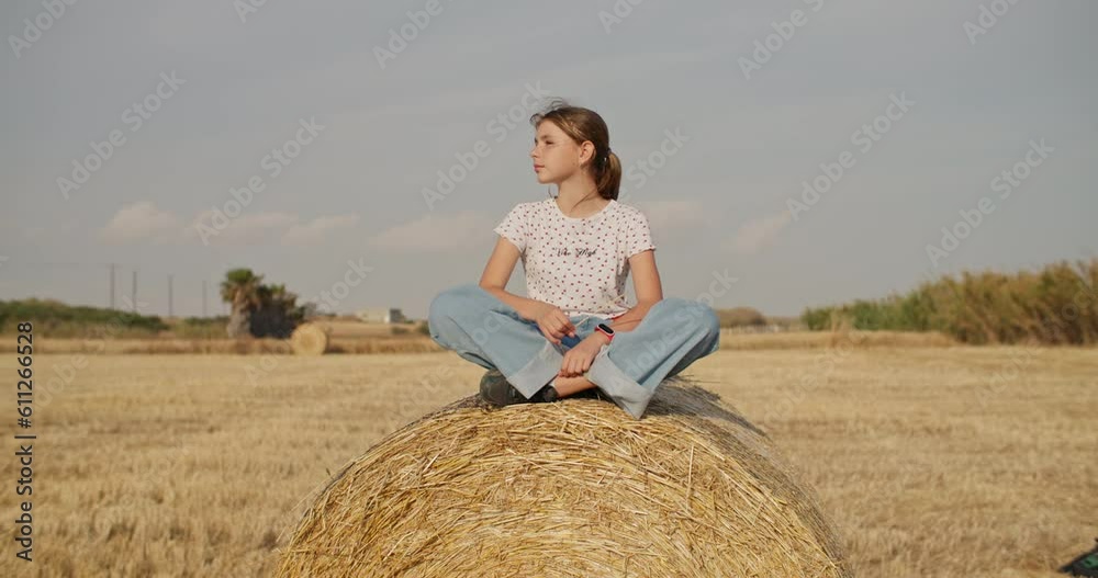 Portrait of a teenage girl leaning on a hay bale in the field. Fashion farm lifestyle, fashionable girl in the village on the field. High quality 4k footage Portrait of a teenage girl leaning on a hay bale in the field. Fashion farm lifestyle, fashionable girl in the village on the field. High quality 4k footage