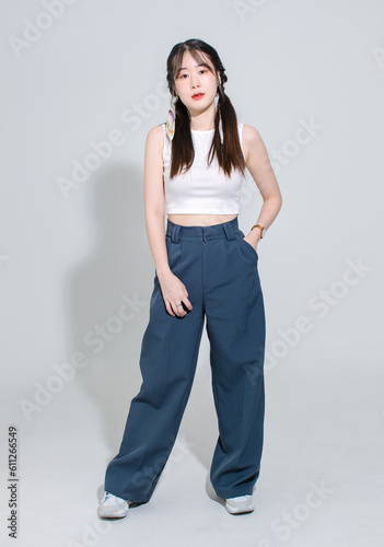 Portrait isolated cutout full body studio shot Asian young pretty female fashion model with pigtails braids hair in fashionable sleeveless crop top standing posing look at camera on white background