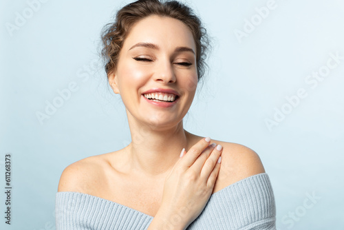 A happy adult woman with  clear skin and a beautiful smile on a blue background in a blue sweater