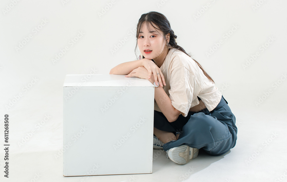 Portrait isolated cutout studio shot of Asian young cute female teenage fashion model with pigtails braids hairstyle in casual trendy wear sitting on floor posing look at camera on white background Portrait isolated cutout studio shot of Asian young cute female teenage fashion model with pigtails braids hairstyle in casual trendy wear sitting on floor posing look at camera on white background