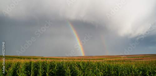 Rainbow in stormy sky. Rural landscape with rainbow over dark stormy sky in a countryside at summer day.