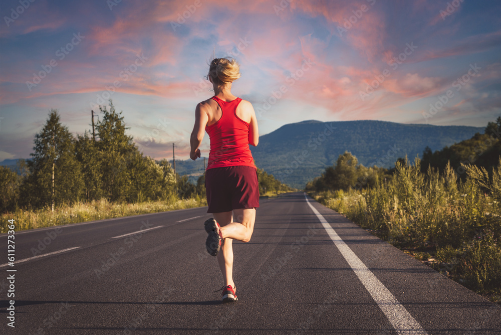 Fitness blonde woman running on the asphalt road at the mountains Fitness blonde woman running on the asphalt road at the mountains