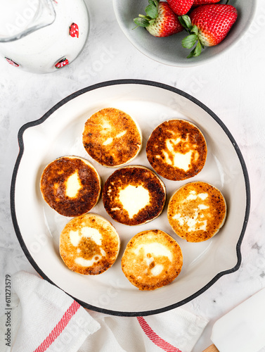 Cottage cheese pancakes, cheesecakes, ricotta fritters in a frying pan with fresh strawberries. Healthy and delicious breakfast for Valentine's Day. Top view, a place to copy.