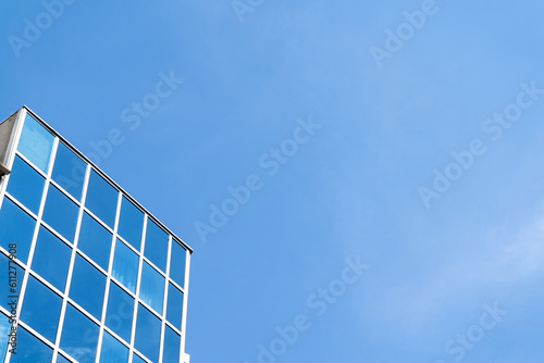 Modern office building with a glass facade and copy space on a blue sky background. Downtown business skyscraper.