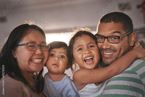 Portrait, laugh and happy family hug in a living room, excited and bonding in their home together. Face, children and parents in a lounge embrace, relax and laughing at funny, comedy and crazy joke