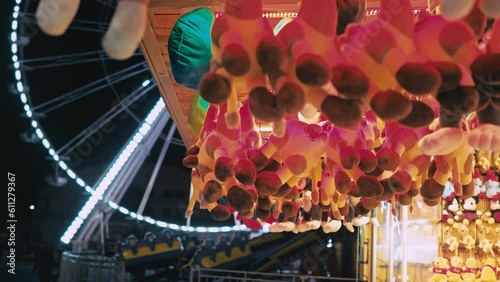 Amusement park location with Ferris wheel on background. Hanging soft toys - awards for well-aimed shots at the shooting range fun fair shooting game. Entertainment for the family