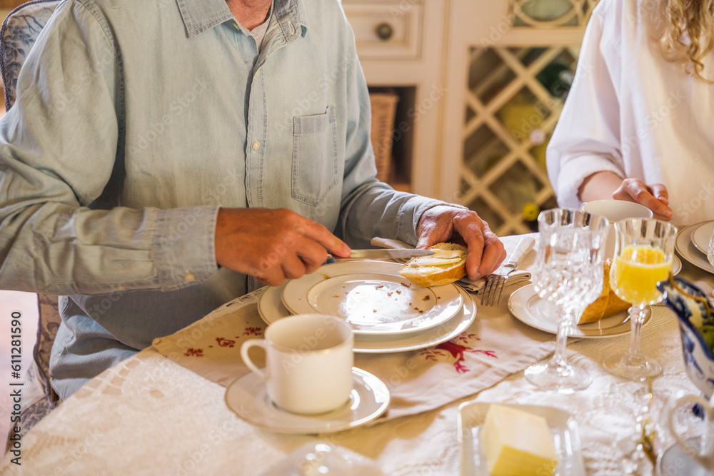 Cropped view of the senior man spreading bread with butter Cropped view of the senior man spreading bread with butter