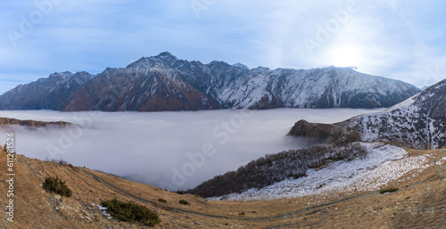 Panorama view of the stunning Caucasus mountains with sea of mist. Beautiful mountain view of the snow-capped peaks near Stepantsminda, Georgia.