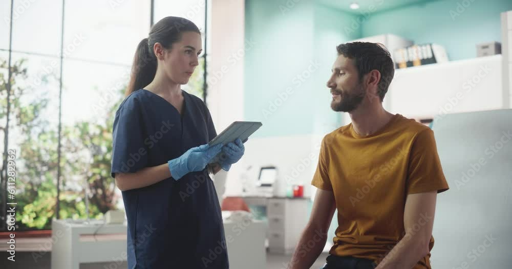Caucasian Man Sitting In The Chair In Bright Hospital And Listening To Female Nurse With Tablet Computer. Professional Woman Explaining Possible Side Effects After Vaccination Or Medicine Injection. Caucasian Man Sitting In The Chair In Bright Hospital And Listening To Female Nurse With Tablet Computer. Professional Woman Explaining Possible Side Effects After Vaccination Or Medicine Injection.