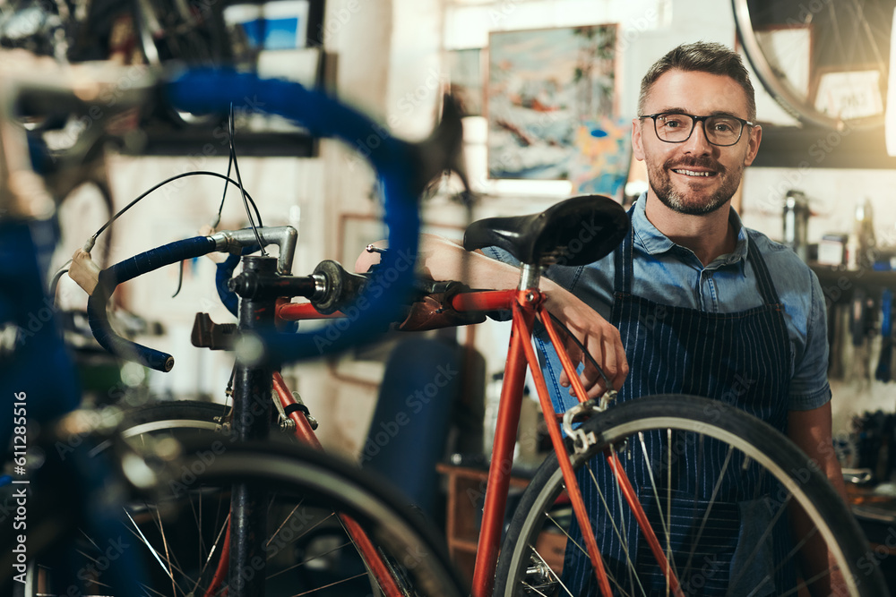 Obraz premium Portrait, happy and repair man in bicycle shop for working in store, cycling workshop and startup. Confident bike mechanic, small business owner and mature male technician with glasses in Australia