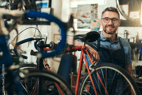 Portrait, happy and repair man in bicycle shop for working in store, cycling workshop and startup. Confident bike mechanic, small business owner and mature male technician with glasses in Australia