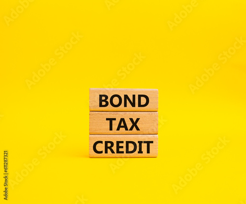 Bond Tax Credit symbol. Concept word Bond Tax Credit on wooden blocks. Beautiful yellow background. Business and Bond Tax Credit concept. Copy space