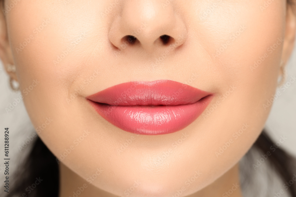 Fototapeta premium Woman with glossy lipstick on light background, closeup