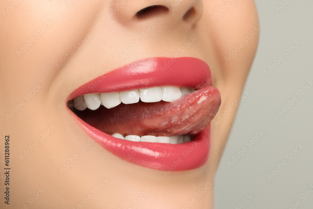 Fototapeta premium Woman showing her tongue on light background, closeup
