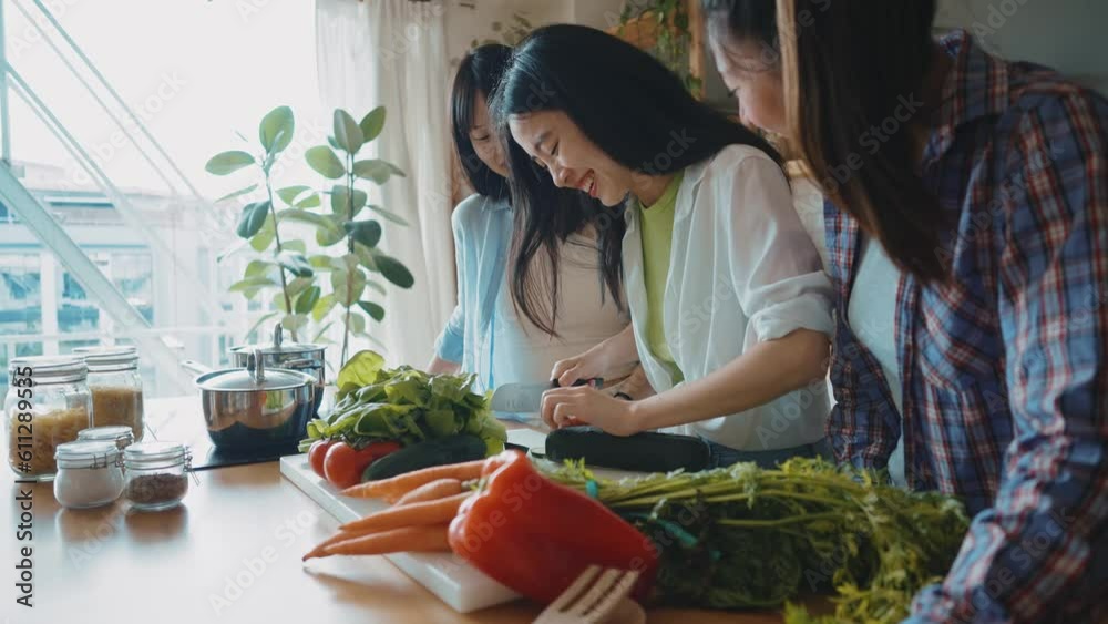 Three happy young women preparing asian food in the kitchen. Group of female friends enjoying their girls day at home cooking an healthy meal with vegetables and organic ingredients. lifestyle concept