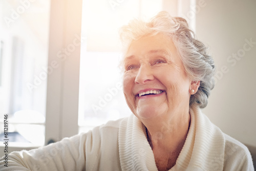 Relax, happy and smile with old woman on sofa for free time, retirement and weekend. Lens flare, happiness and mindset with senior person in living room at home for elderly, positive and carefree