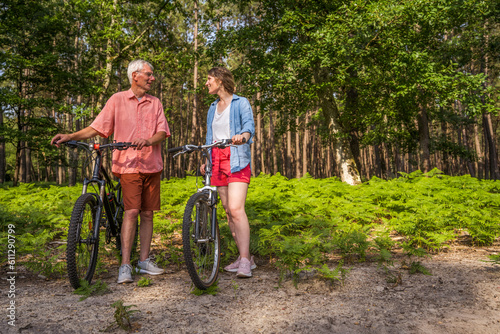 Happy family of senior father and adult daughter enjoying a summer bicycle ride and speaking