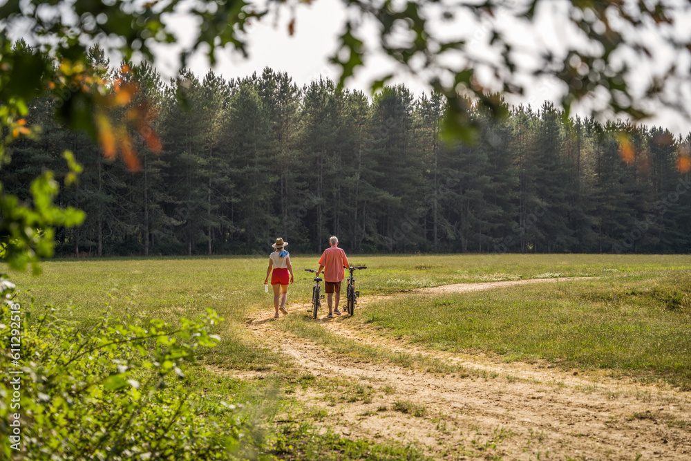Fototapeta premium Mature man and his adult daughter walking with bikes