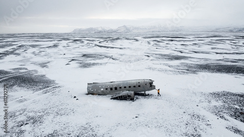 Woman dressed for winter in front of the wreck of the crashed plane in Iceland, on the beach of Sólheimasandur.