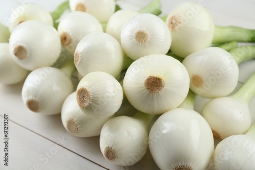 Whole green spring onions on white wooden table  closeup