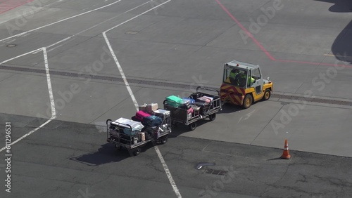 Trailer truck full of suitcases on the runway. Workers carry suitcases to load on the plane.