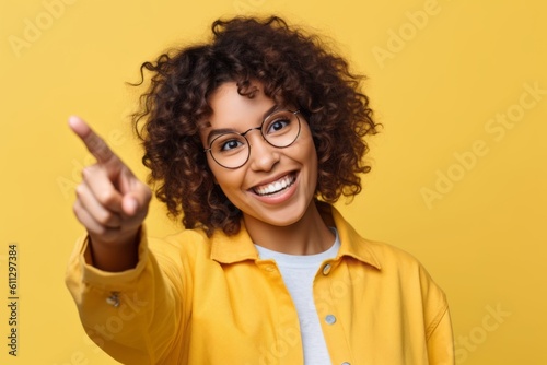 Close-up portrait photography of a joyful girl in her 20s raising a finger as if having an idea against a pastel yellow background. With generative AI technology