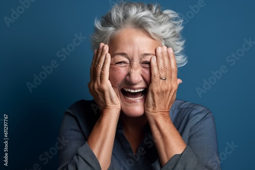 Headshot portrait photography of a happy mature woman putting hands on the face in a gesture of terror against a soft blue background. With generative AI technology