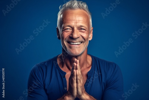 Medium shot portrait photography of a grinning mature man doing a yoga pose against a sapphire blue background. With generative AI technology