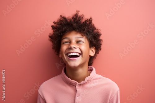 Medium shot portrait photography of a happy kid male laughing against a coral pink background. With generative AI technology