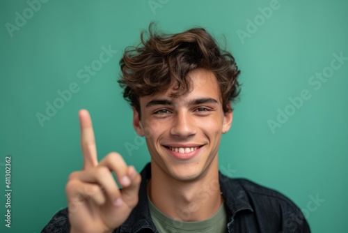Headshot portrait photography of a satisfied boy in his 20s making a peace and love gesture with the fingers against a spearmint green background. With generative AI technology