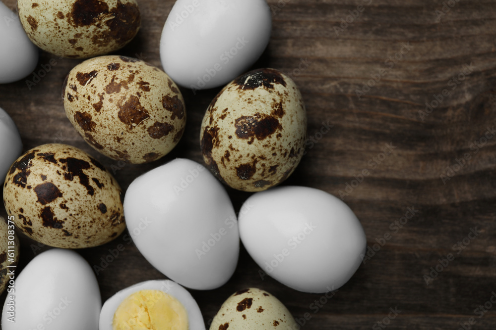 Peeled and unpeeled hard boiled quail eggs on wooden table, flat lay. Space for text