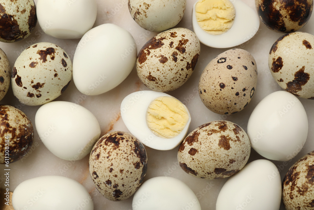 Unpeeled and peeled hard boiled quail eggs on light table, flat lay