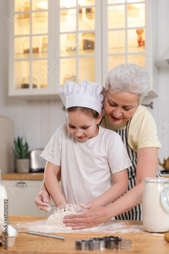 Wallpaper Mural Happy family in kitchen. Grandmother and granddaughter child cook in kitchen together. Grandma teaching kid girl knead dough bake cookies. Household teamwork helping family generations concept Torontodigital.ca