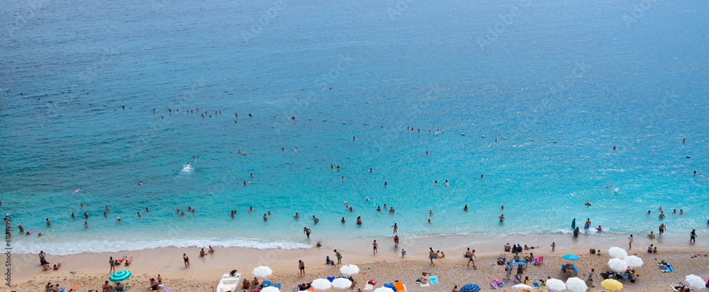 Aerial view people relaxing on the beach. Sandy beach with colorful umbrellas, people swimming in the sea bay with clear blue water. Aerial view people relaxing on the beach. Sandy beach with colorful umbrellas, people swimming in the sea bay with clear blue water.