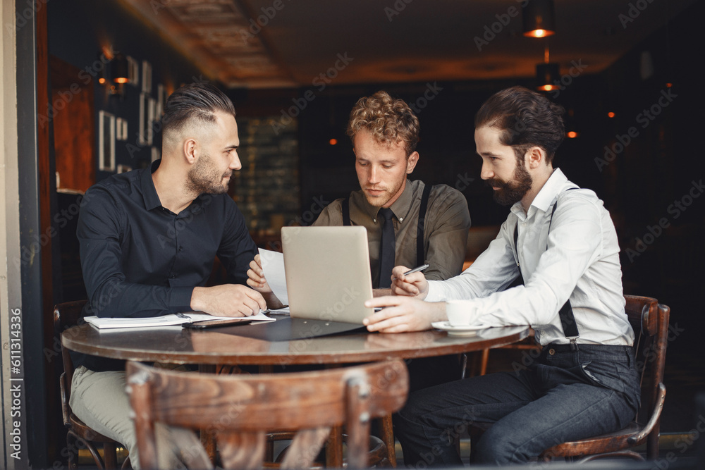 Three men are sitting at a table and talking to each other.