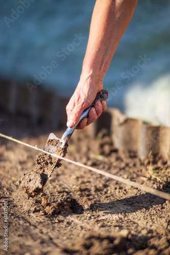 Farmer cultivating land in the garden with hand tools. Soil loosening. Gardening concept. Agricultural work on the plantation
